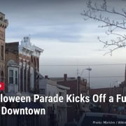 Storefronts along a street in downtown Tiffin, Ohio, with headline: Tiffin Halloween Parade Kicks Off a Full Saturday Downtown